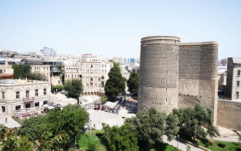 Aerial view of the round stone Maiden Tower among the old houses and trees of Baku's Old City