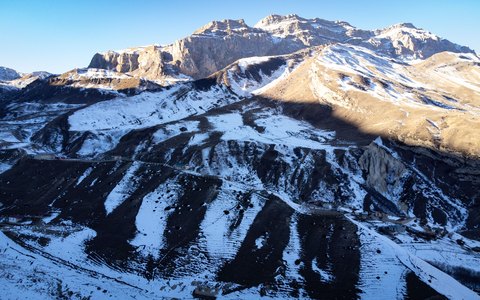 Snow-covered mountain ridges near Laza in the Qusar district, lit by low sun under a blue sky