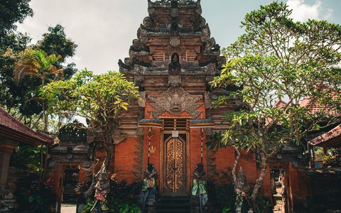 Carved red-brick gateway framed by trees at Ubud Palace