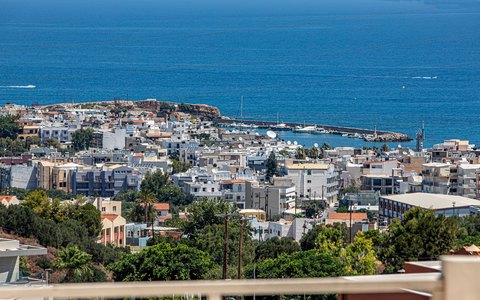 Aerial view of the white town and harbour of Hersonissos beside a deep blue sea