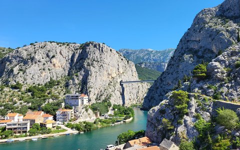 The Cetina River running out of a steep grey gorge past the houses of Omis, under a clear blue sky