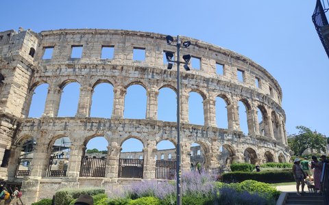 The arched stone walls of the Roman amphitheatre in Pula under a clear summer sky