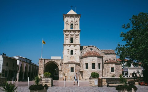 The stone church of St Lazarus with its tall bell tower under a clear blue sky
