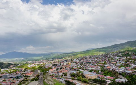 A high view over the town of Gori and green hills under a sky of white clouds