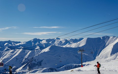 Snow-covered Caucasus peaks above the ski slopes of Gudauri under a deep blue sky
