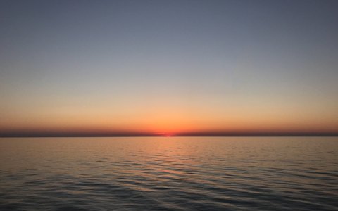 The sun setting over a calm Black Sea at Kobuleti under a clear evening sky