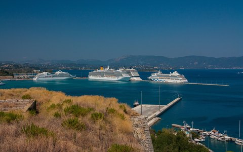 Cruise ships at the quay in Corfu harbour on a clear summer day, with mountains across the water