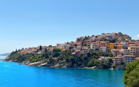 The old town of Kavala on a green headland above bright blue water, under a clear sky