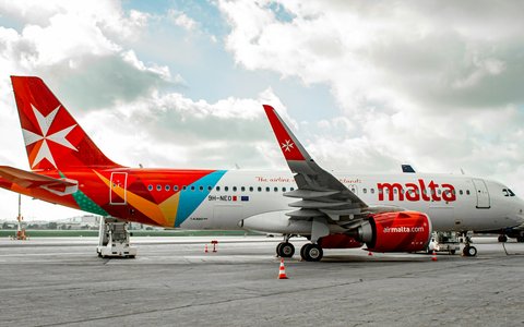 Zwei rot-weiße Verkehrsflugzeuge auf dem Vorfeld des Flughafens Malta unter bewölktem Himmel