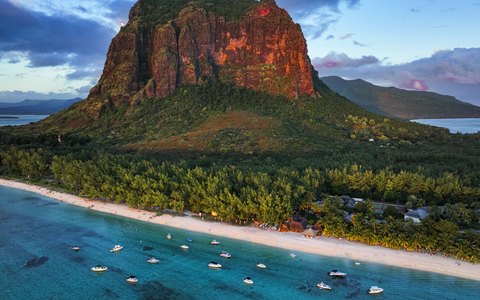 Aerial view of the Le Morne Brabant mountain above palm trees, a white beach and turquoise lagoon