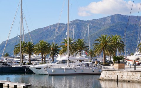 Yachts moored in the marina at Tivat with green mountains behind under a blue sky