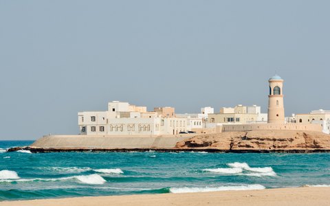 The lighthouse and traditional buildings on the coast at Sur beside blue water