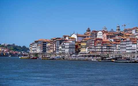 The colourful houses of Porto's Ribeira district rising above the Douro river, under a blue sky