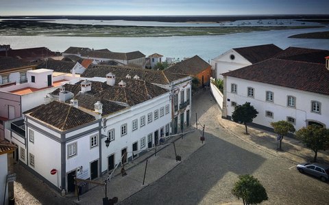 Old white and tiled buildings of Tavira along the river under a clear blue sky
