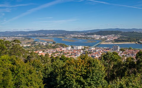 A high view over Viana do Castelo, the Lima river and green hills, under a blue sky