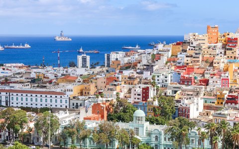 Colourful houses spread across the hills of Las Palmas with ships on the blue Atlantic beyond
