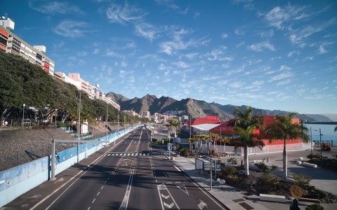 A seafront avenue in Santa Cruz de Tenerife lined with colourful buildings, with mountains and a blue sky behind