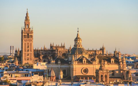 Giralda und Kathedrale von Sevilla über den Stadtdächern im warmen Abendlicht