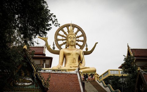 Golden seated Big Buddha statue above temple roofs on Koh Samui