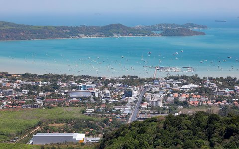 Aerial view of Karon beach and town beside turquoise water with hills around the bay