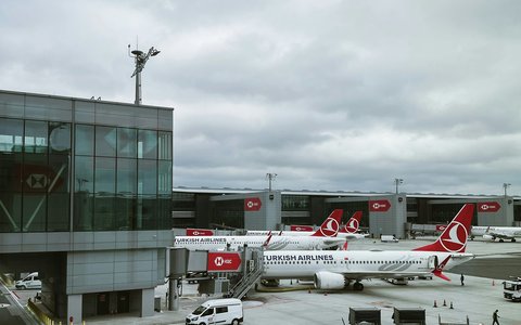 Rote und weiße Verkehrsflugzeuge auf dem Vorfeld am Terminal des Flughafens Istanbul unter bewölktem Himmel