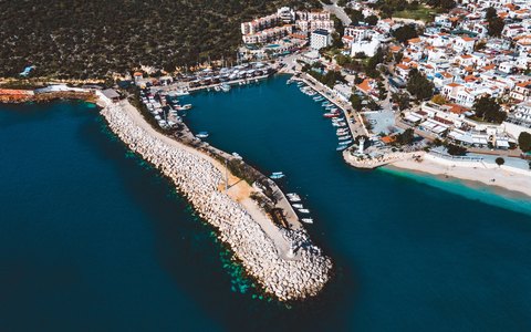 Aerial view of Kalkan's harbour wall, moored boats and white houses beside turquoise water
