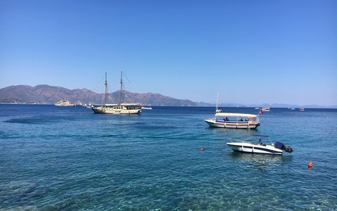 Boats on the calm blue water of Marmaris bay with hills behind, under a clear blue sky