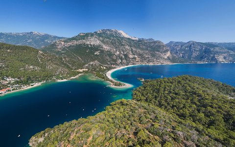 Aerial view of the turquoise Blue Lagoon and beach at Oludeniz, with forested hills and mountains behind
