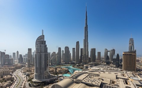 Aerial view of Downtown Dubai with the Burj Khalifa rising above the towers, under a clear blue sky